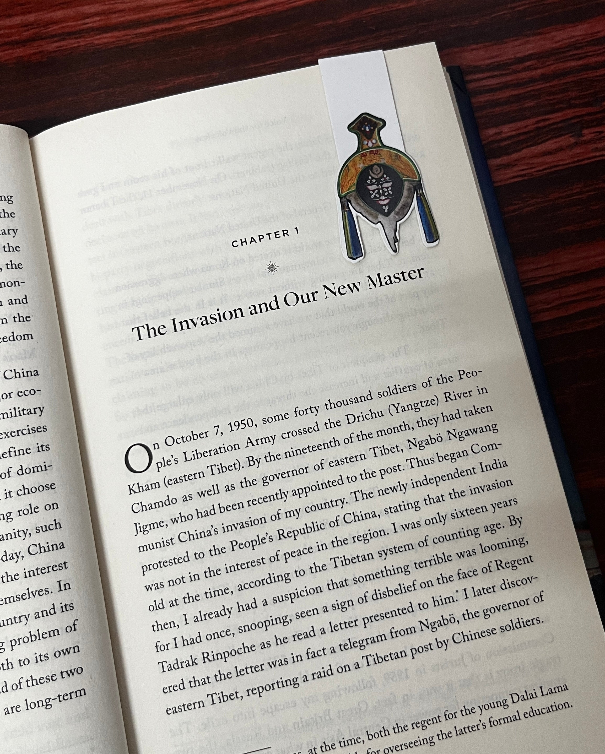 Open book with a tashi shopa mask on a wooden surface