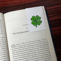 Book open to a page with a four-leaf clover magnetic bookmark