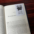 Book with a bookmark featuring 'Tashi Delek' on a wooden surface